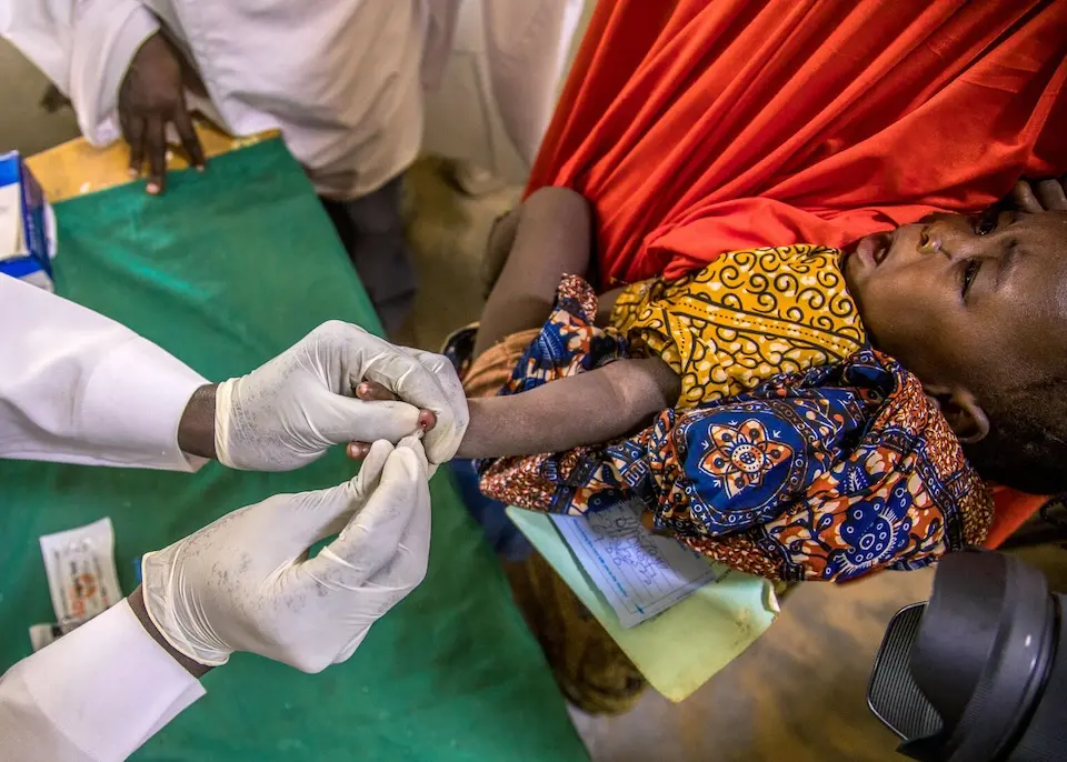 A health worker conducts a malaria test on a sick child in Dumbegu, Nigeria.