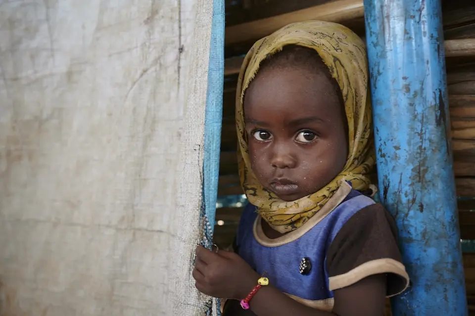 A girl peeks out from a tent flap at a UNICEF child-friendly space in Tawila, North Darfur, Sudan.