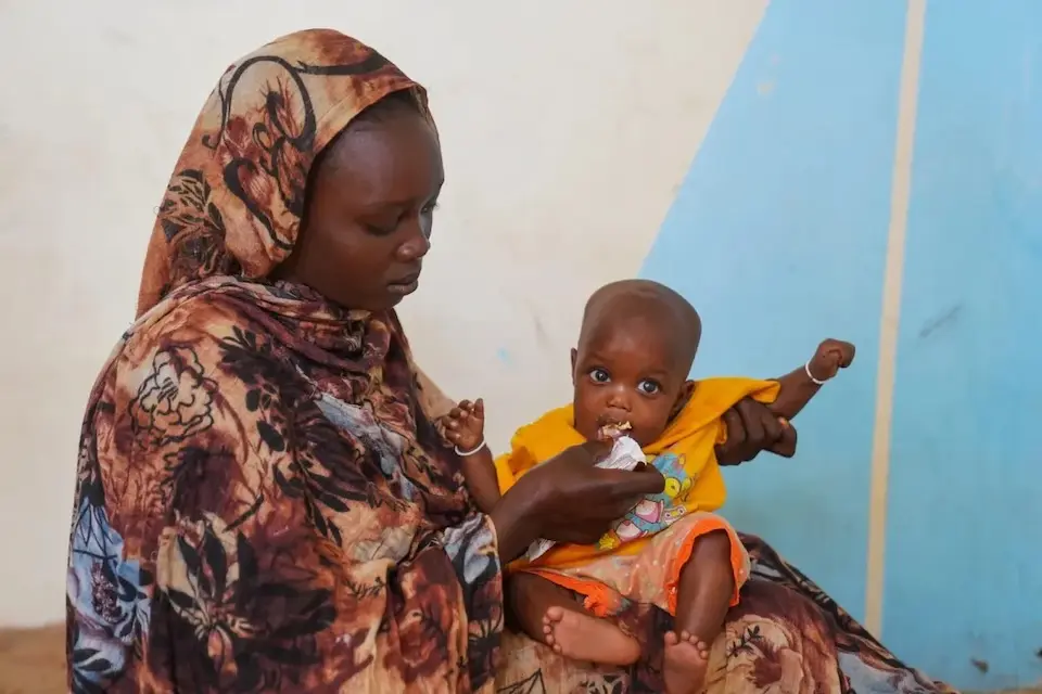 At a displacement camp in Sudan, a mother feeds her infant ready-to-use therapeutic food provided by UNICEF to treat severely malnourished children.
