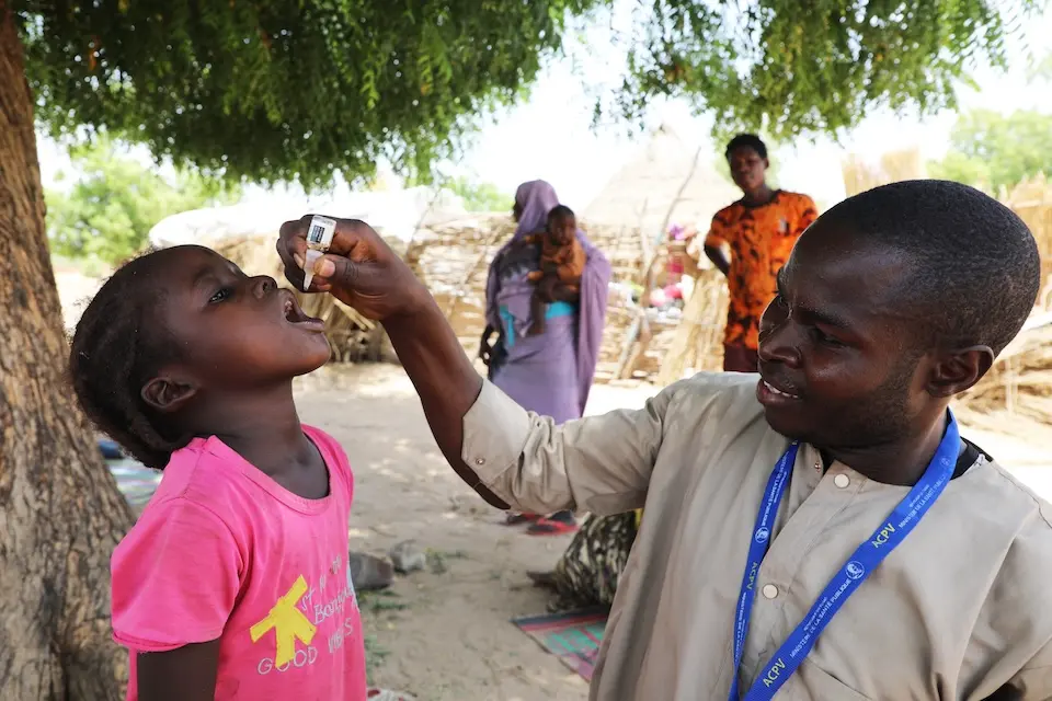 A young girl receives the oral polio vaccine from a UNICEF-supported health worker in Chad.