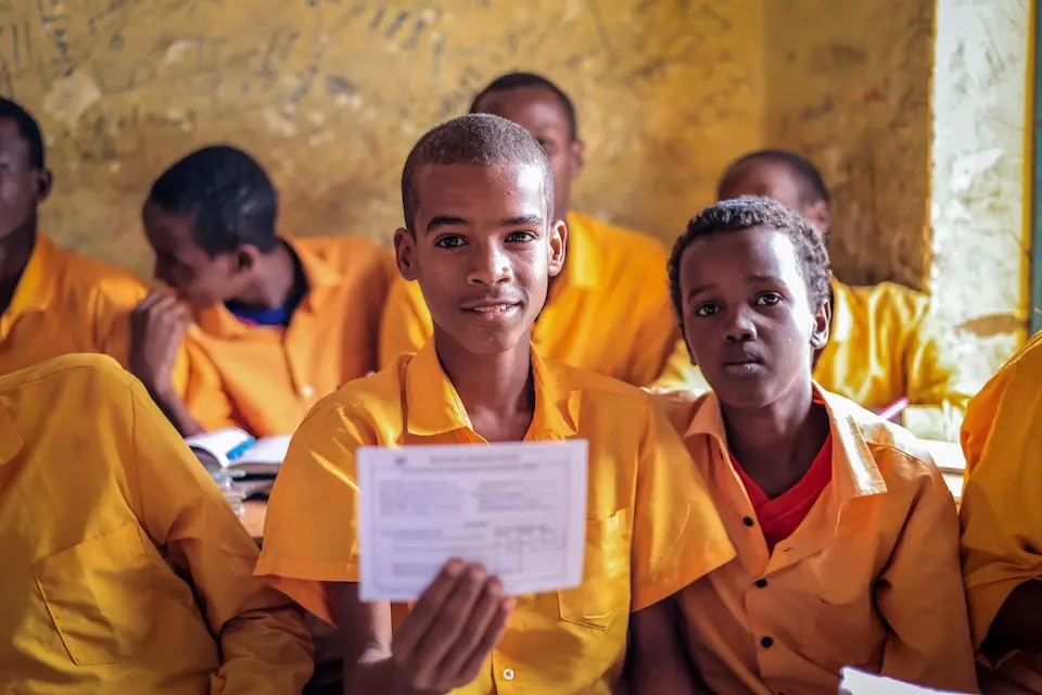 Mohamed presents his vaccination card during a school-based diphtheria immunization session in Somalia, supporting documentation and follow-up for child health services. 