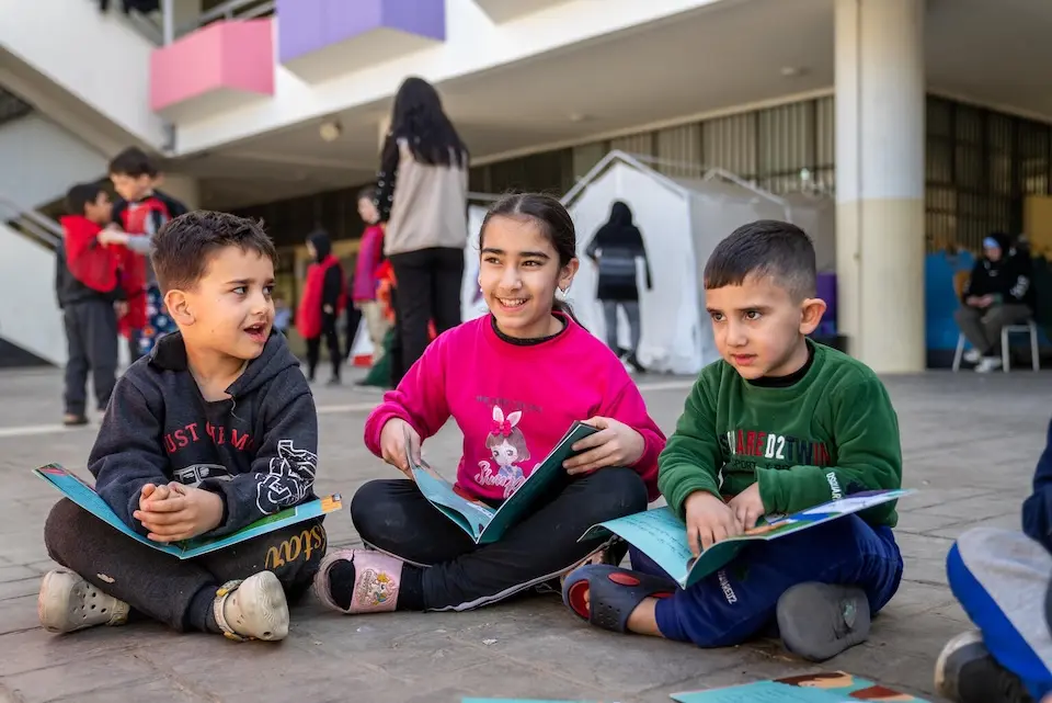 Three children sit reading books together at school in Beirut, Lebanon