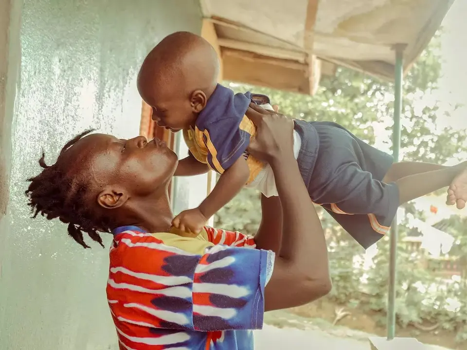 A mother holds her baby high and kisses him on the nose in Sierra Leone.