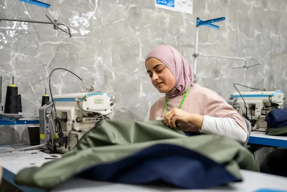 A youth sews a sleeping bag to help displaced families in Lebanon. 