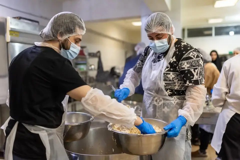 Two youth volunteers prepare food for families staying in a temporary shelter in Lebanon. 