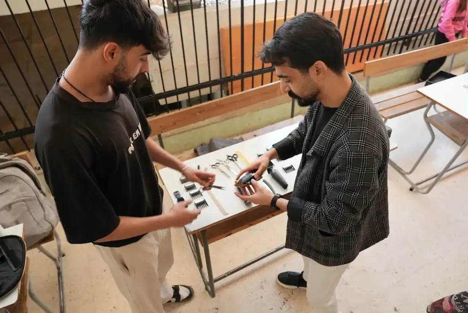 Youth prepare their tools to offer haircuts and beard trims to people displaced by the war in Lebanon. 