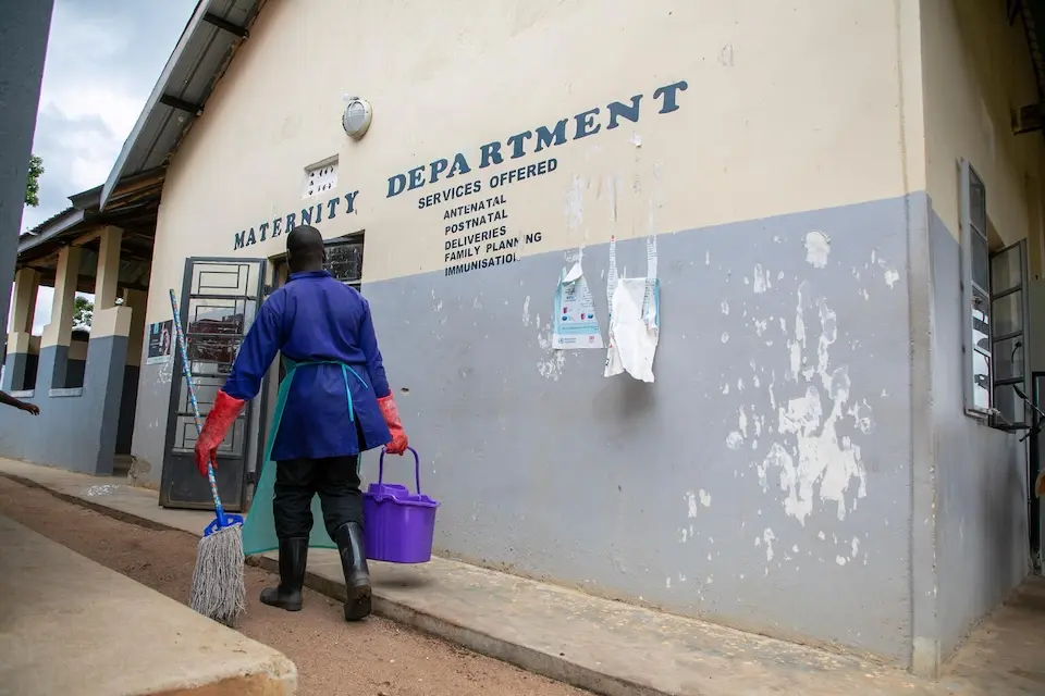 A man carries cleaning supplies into a hospital in Uganda.