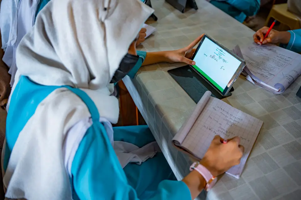 Student taking notes from information she is reading off a digital tablet
