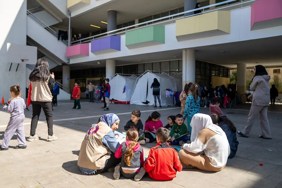 Displaced children sit in a circle with caregivers at Omar Faroukh School in Beirut on March 17, 2026. 