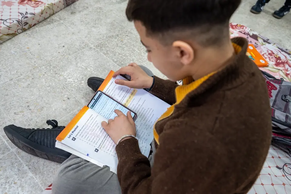 A child studies using a workbook and a cellphone in Lebanon. 