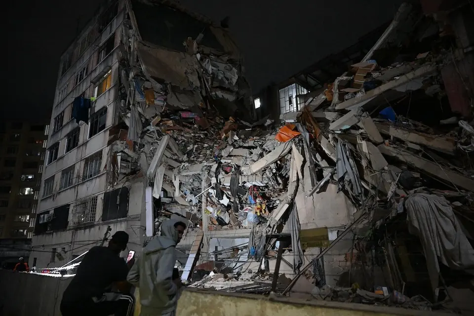 People look at a collapsed building in the Altamira neighborhood following an earthquake in Caracas on June 24, 2026. 