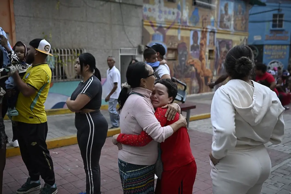 A woman comforts a child in the street following an earthquake in Caracas on June 24, 2026. 