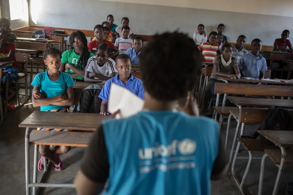 UNICEF staff person talks to students in a classroom in Sofala, Mozambique.