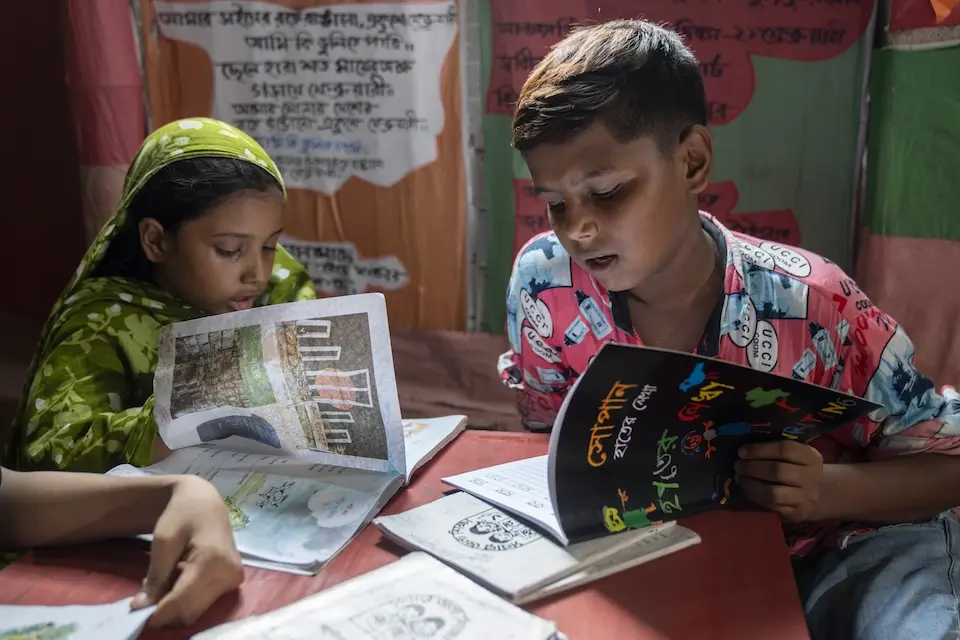 A girl and boy reading schoolbooks at a shared table.