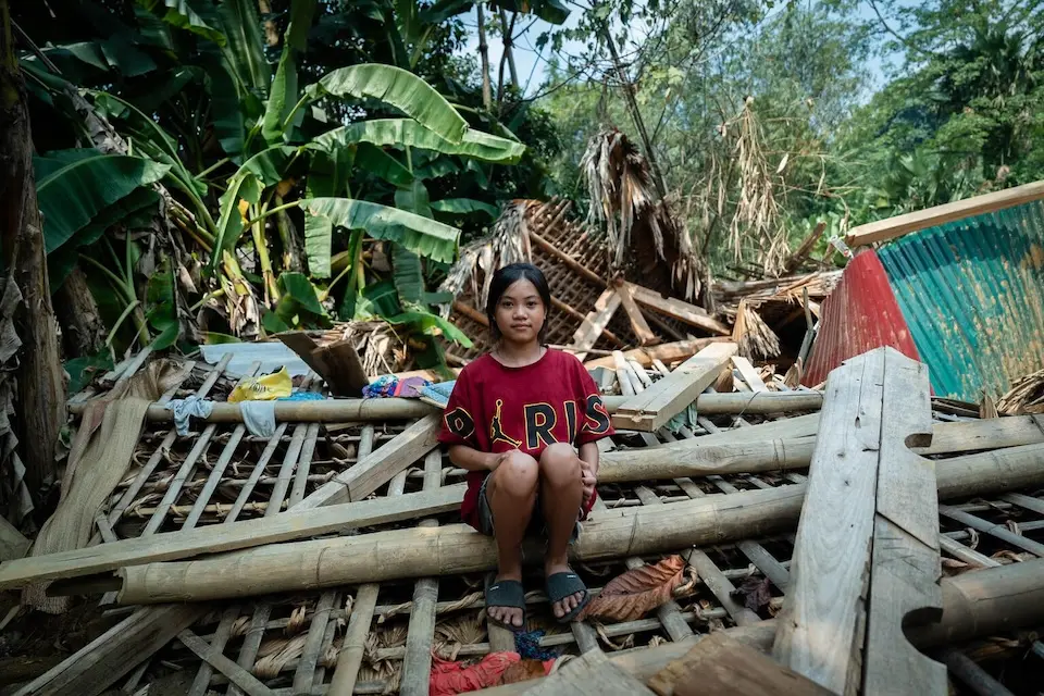 13-year-old girl in Vietnam sits among the ruins of her house destroyed by a landslide caused by a typhoon..