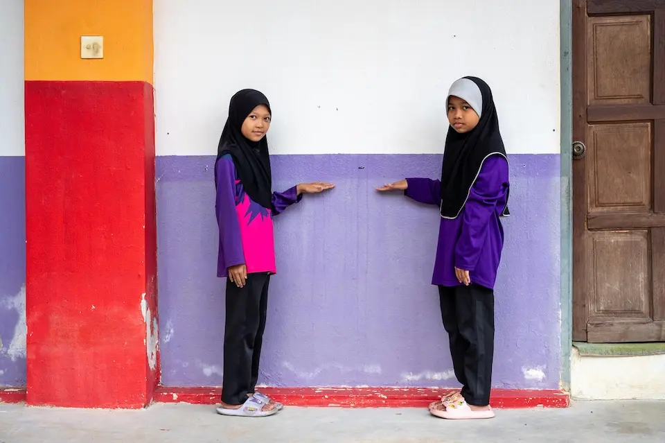 Two students in eastern Malaysia point to the watermark left by flooding that overtook their school.