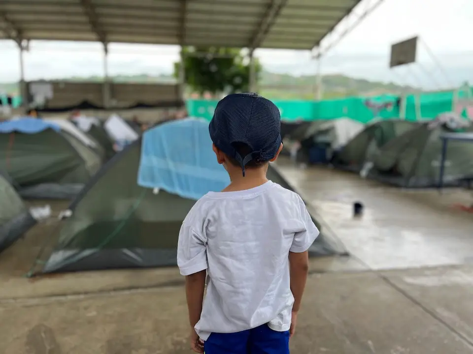 A boy stands near some tents in Cúcuta that are being used for shelter by families displaced from the Catatumbo region, Colombia.