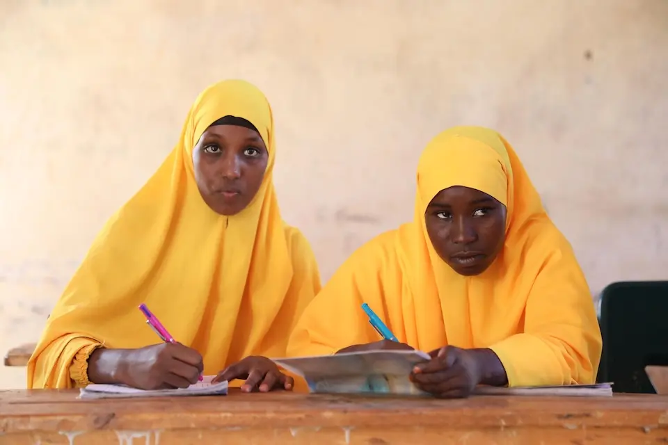 Two teenage girls attend class at Kabasa Primary School in Somalia. The school serves children from displaced and host communities.