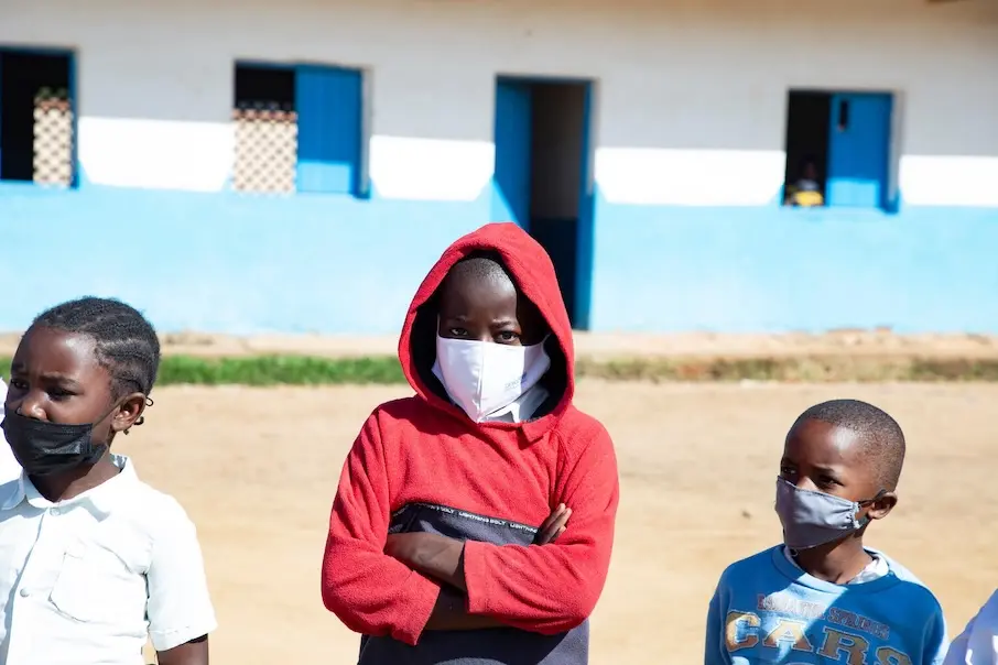 Three young boys in DR Congo wear masks in the courtyard outside their school.