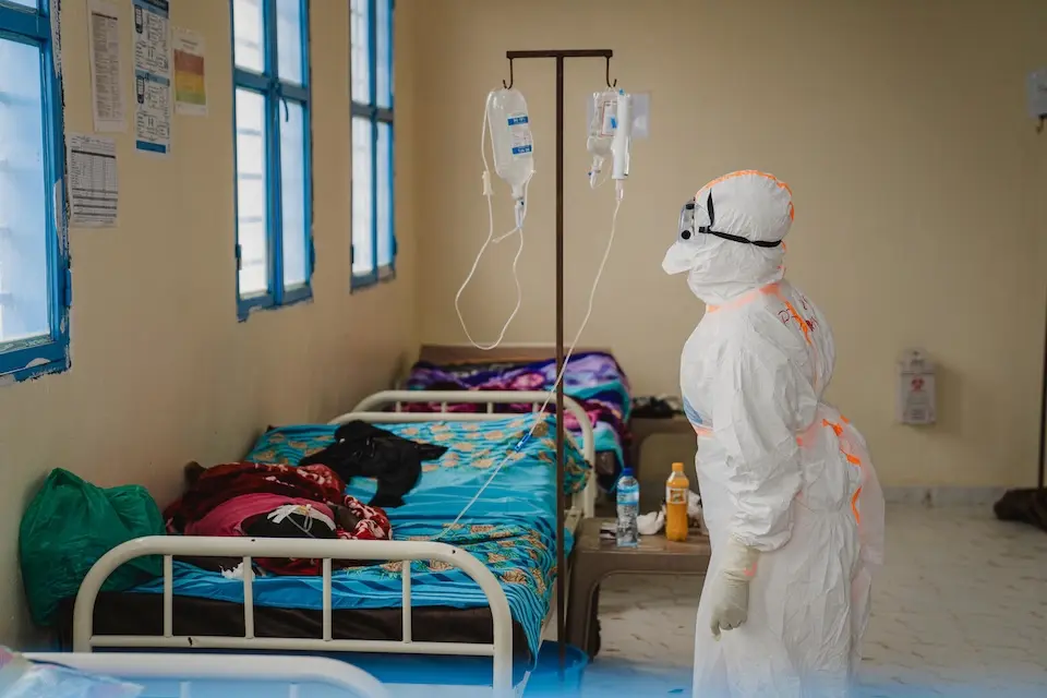 A UNICEF-supported worker wears head-to-toe personal protective equipment at the bedside of a patient at an Ebola treatment center in Bunia, Ituri province, DRC.