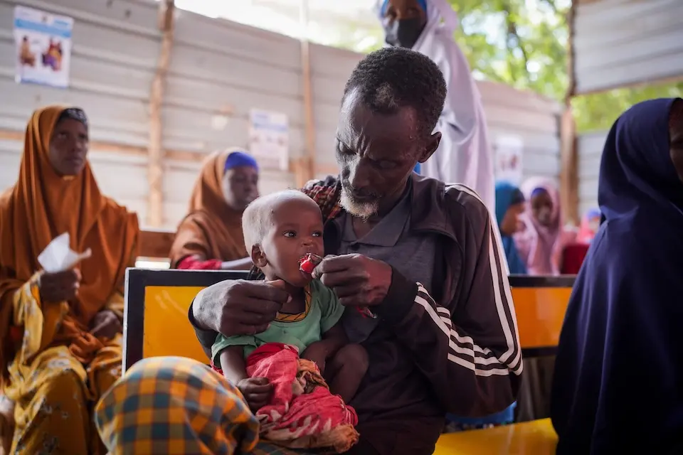 A caregiver feeds a malnourished child ready-to-use therapeutic food Burhakaba, Bay Region, Somalia.