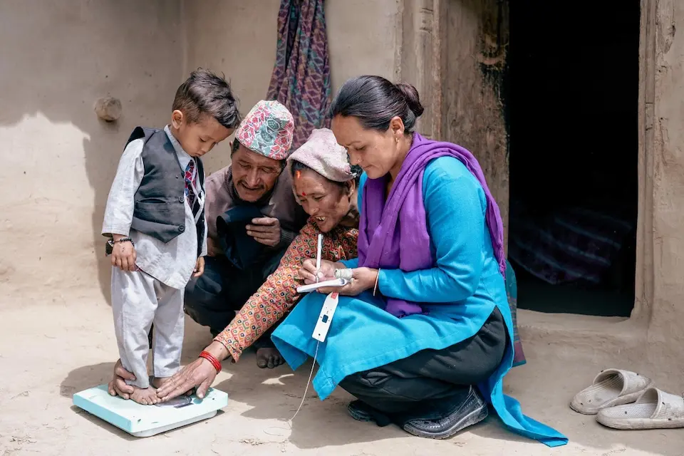 A UNICEF-supported health worker checks the weight of a child recovering from malnutrition in Nepal. 
