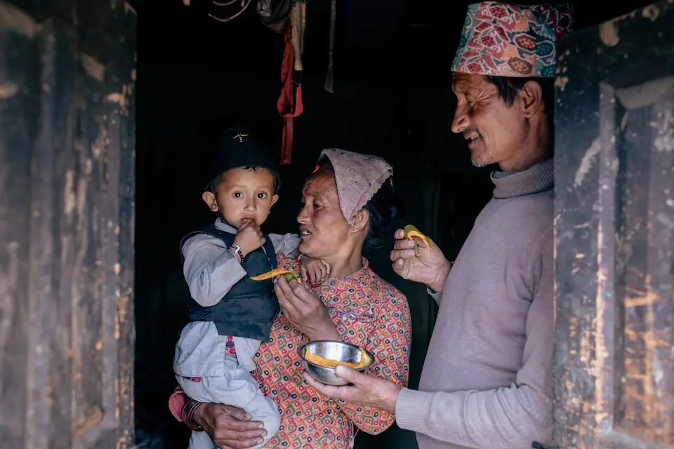 A 2-year-old eats a mango slice while his parents watch in Dolpa District, Nepal. 