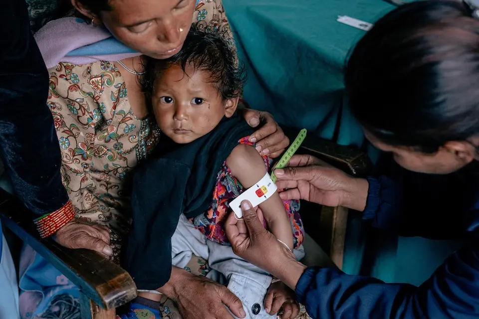 A health worker measures a 1-year-old mid-upper arm circumference during a checkup in Dolpa District, Nepal.