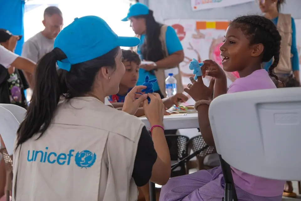 A UNICEF staff person engages with a young girl at a child-friendly space in La Guaira, Venezuela.