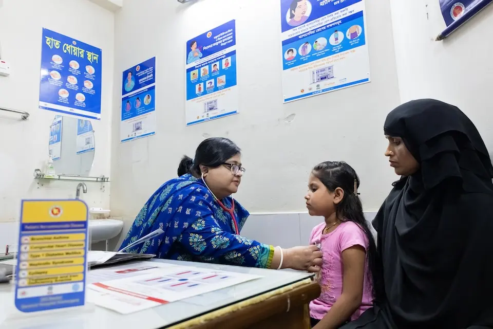 A health worker uses a stethoscope to listen to a girl's heart during a checkup in Bangladesh. 