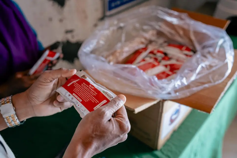 At a local health post in Juphal, Nepal, a UNICEF Nutrition Officer hands over Ready-To-Use Therapeutic Food to a community health worker. The RUTF will be used to treat children in the area with severe acute malnutrition. 