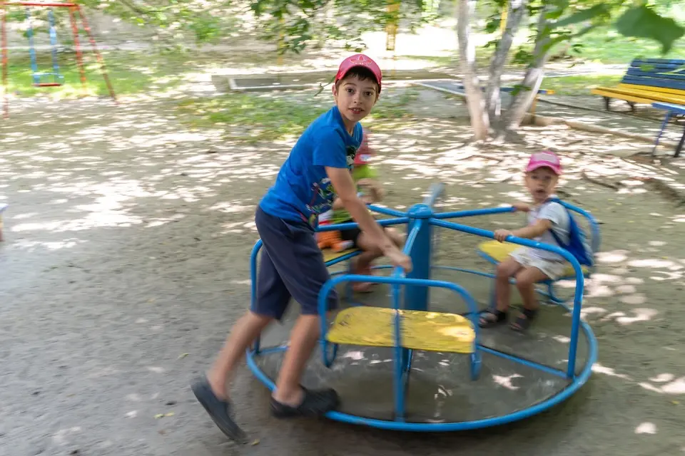 Children play in a Kyiv park littered with shrapnel after aerial assaults in July 2026.
