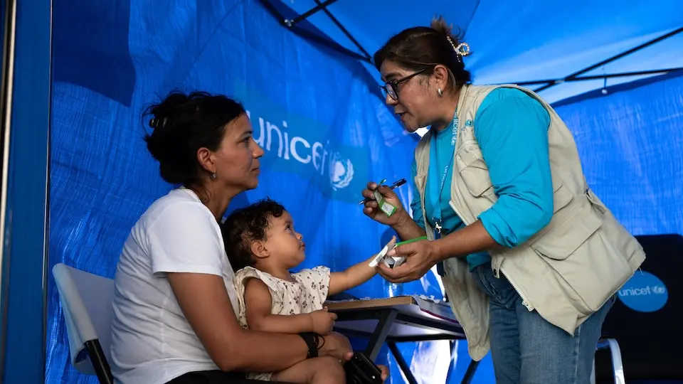 A mother and baby displaced by the June 2026 earthquakes receive help from a UNICEF-supported humanitarian worker in La Guaira, Venezuela.