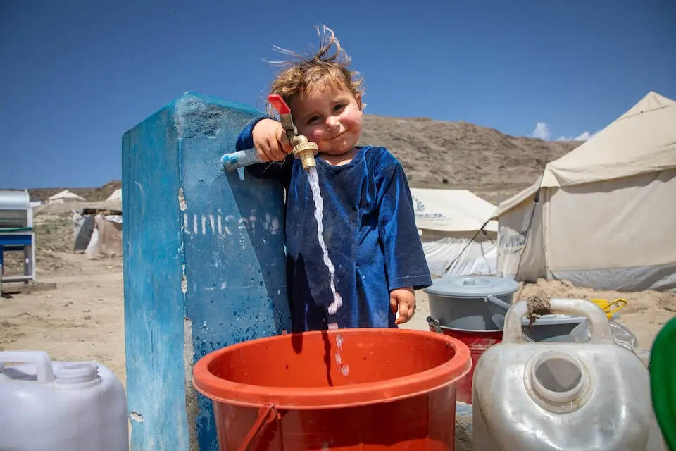A 4-year-old girl in Afghanistan fills a bucket from a safe water tap provided by UNICEF.