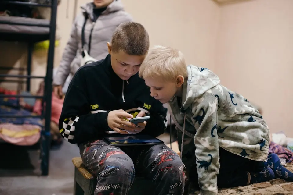 Two brothers in Kherson, Ukraine, look at a mobile phone.