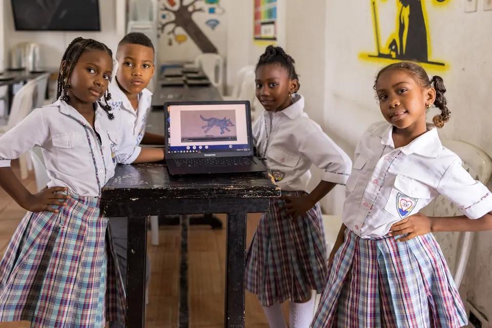 At a school in Colombia, students wearing uniforms stand beside a digital textbook. 