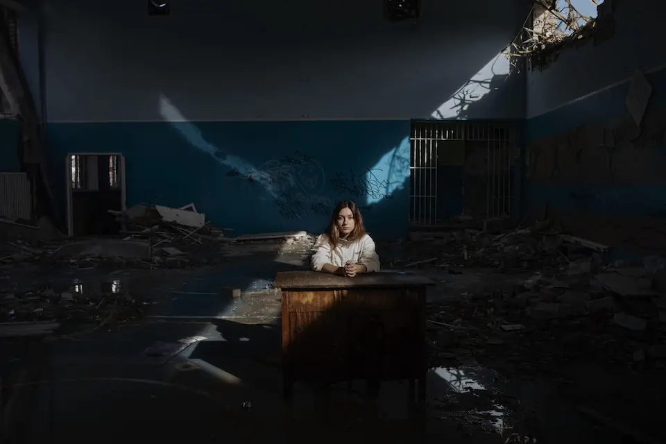 A girl sits inside her destroyed school in Ukraine.