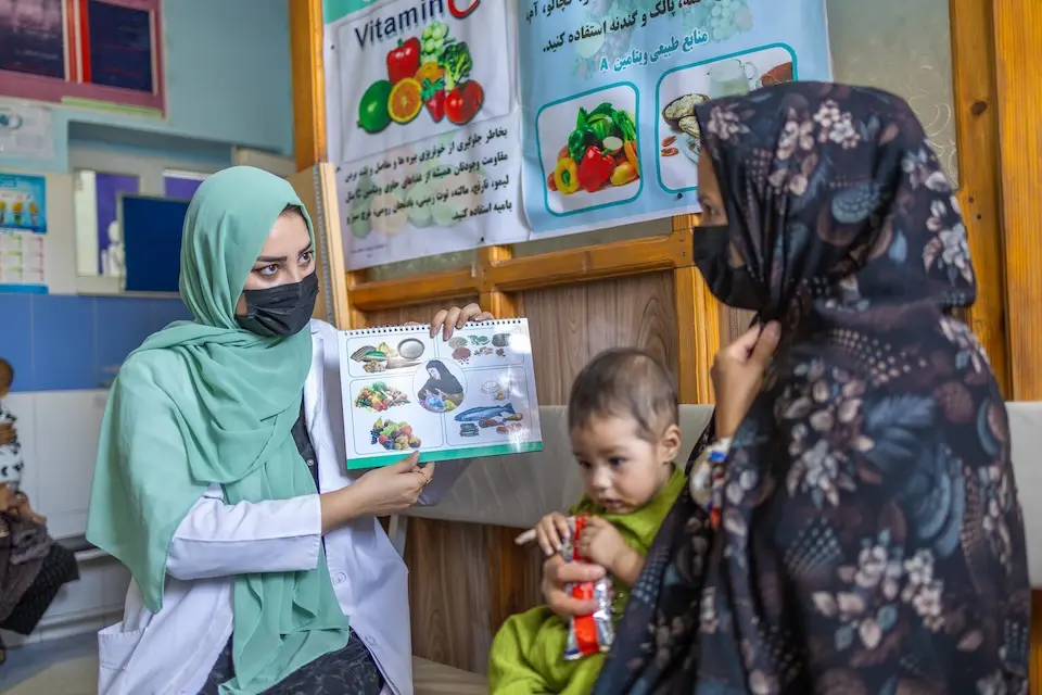 A nutrition nurse at a UNICEF-supported clinic in Herat, Afghanistan, provides guidance and advice to a mother on how to feed children and prepare nutritious food for babies. 