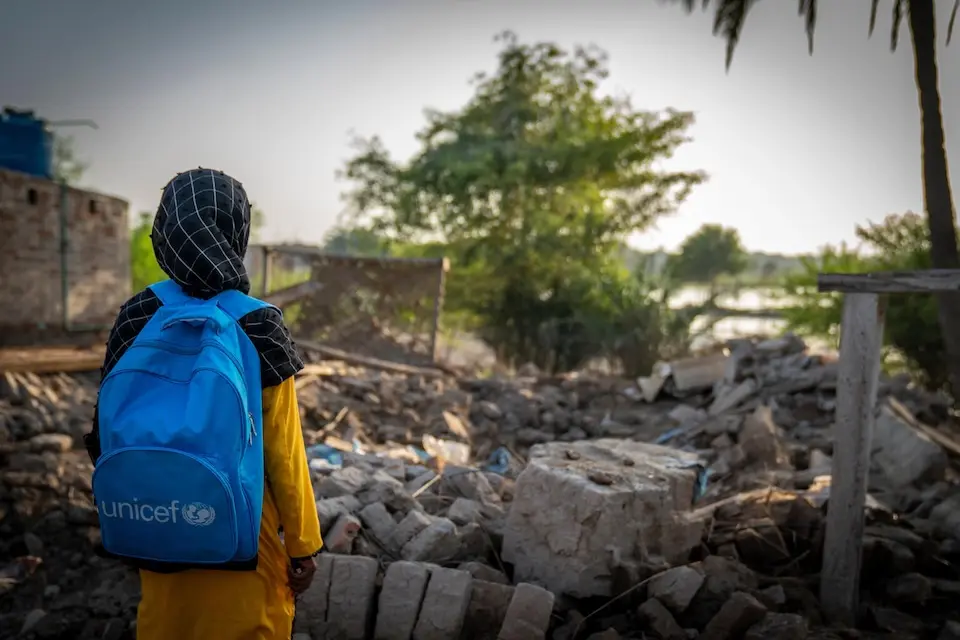 A girl in Pakistan looks at the remains of a house destroyed by a flood.