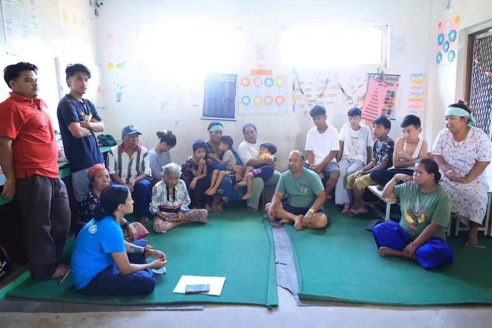 A UNICEF staff member meets with families displaced by flash flooding in Nepal. 