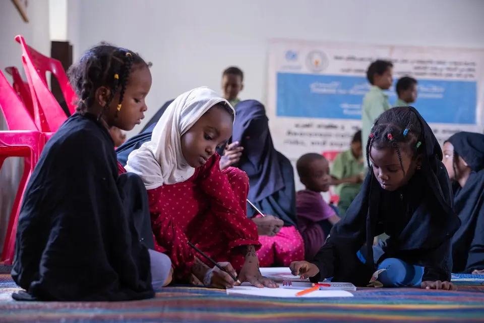 Three young girls draw together inside a UNICEF-supported child-friendly space in Khartoum, Sudan.