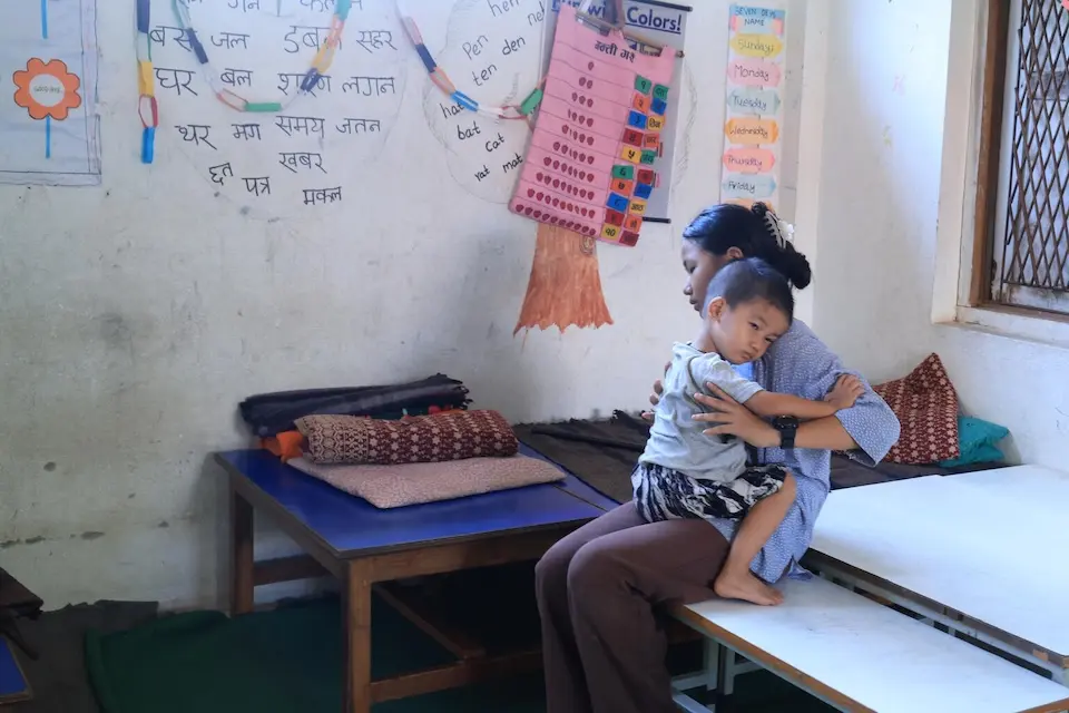 A teenage girl and her 3-year-old brother in the classroom where their family is living after massive flooding swept away their home in Bhaise, Nepal. 