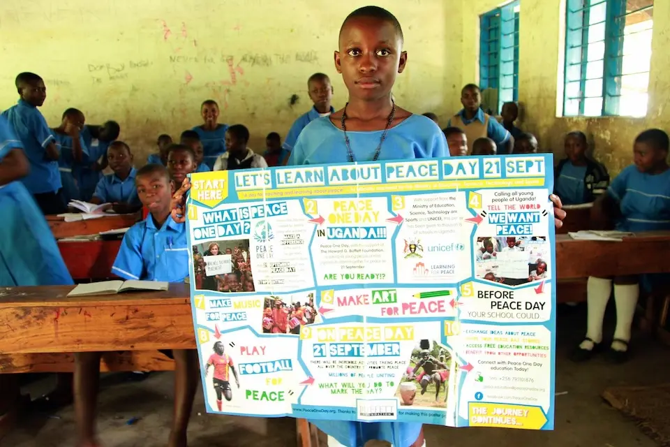 A student of Buhundu Primary School in Western Uganda displays a poster for the International Day of Peace.© UNICEF / UNI199715 / Stephen Wandera)
