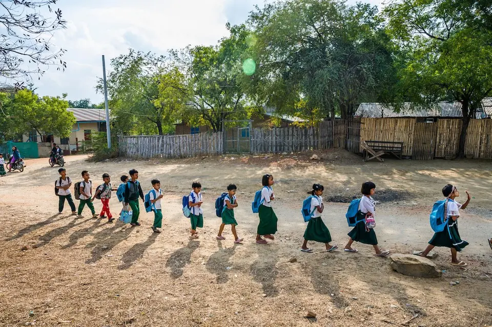 Primary school students in Mandalay region, Myanmar, walk single file carrying UNICEF backpacks. 