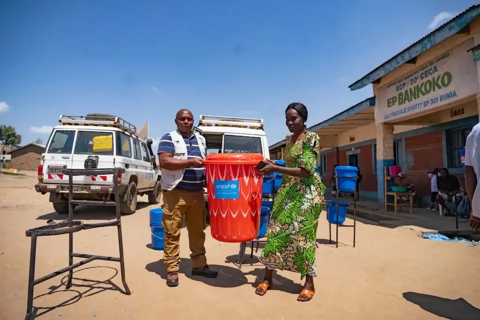 A man and woman in Ituri, DR Congo, carry a big bucket of supplies provided by UNICEF to support the Ebola response..