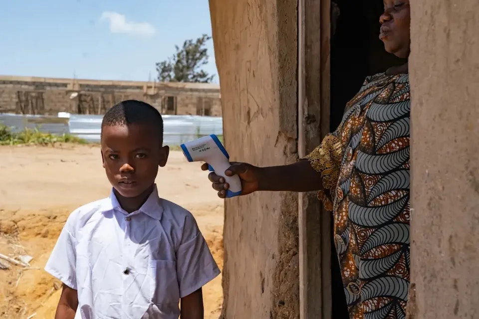 In DR Congo, a teacher checks a child's temperature upon arrival at school, an Ebola-prevention tactic.