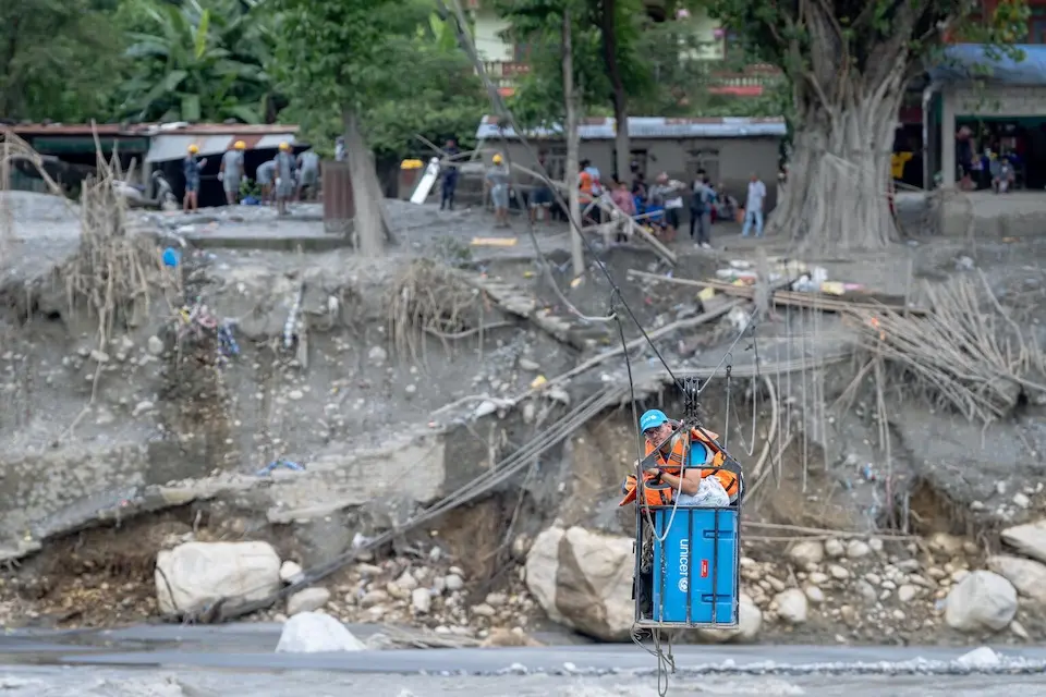 On Sept. 12, 2026, a UNICEF cold chain specialist crosses a fast-flowing river using a manually operated ropeway to deliver oral cholera vaccine doses for children after devastating flooding in Nepal. 