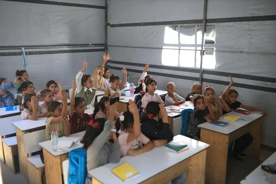 Children raise their hands to answer the teacher's question in a UNICEF specialized learning tent in the Gaza Strip on Sept. 21, 2026.