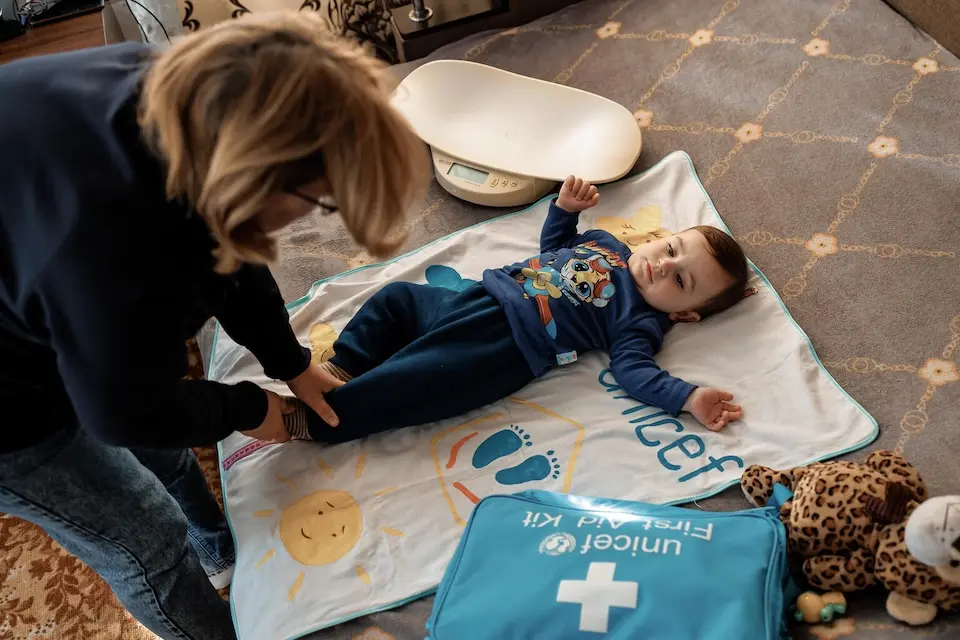 A UNICEF-supported nurse conducts a health check-up for 10-month-old Danii during a home visit in Vyrishalne, Poltava region, Ukraine.