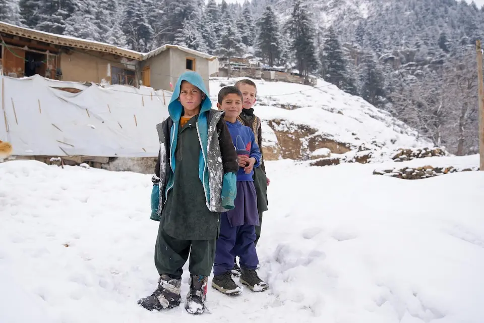 Children stand in the snow outside their home in Parun, Nuristan, Afghanistan. 